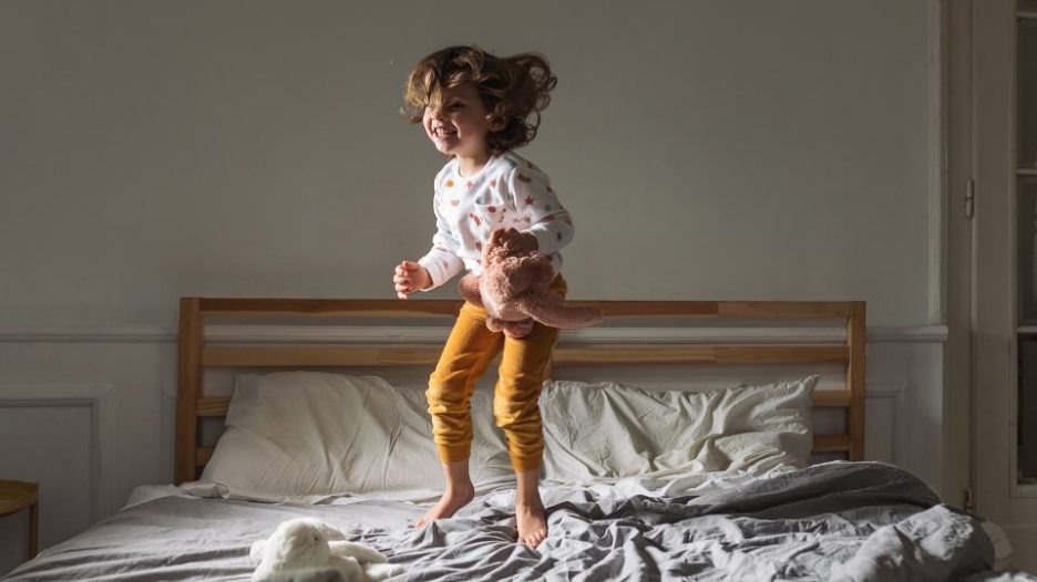 young child in pyjamas jumping on their parent's bed