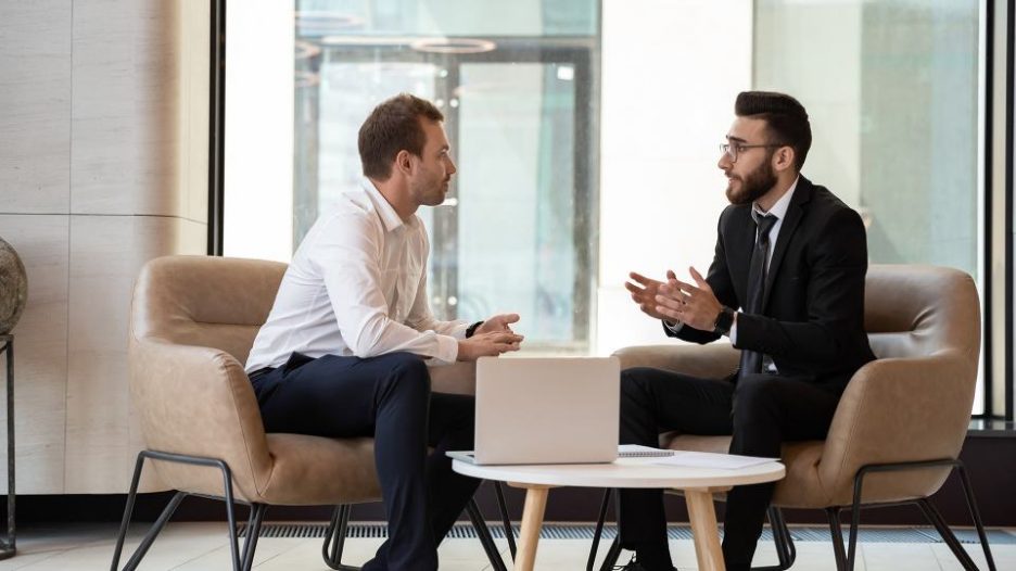 two men having an informal meeting in comfortable office chairs in a modern setting