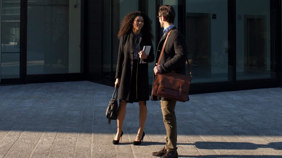 Young business people talking together outside of a corporate building.