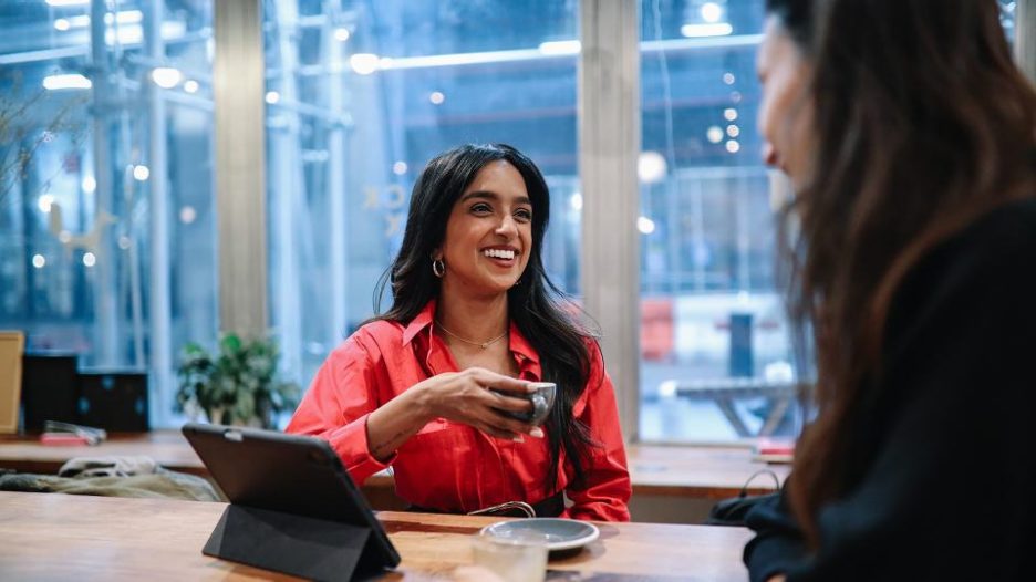 adviser in red shirt drinking coffee talking to client