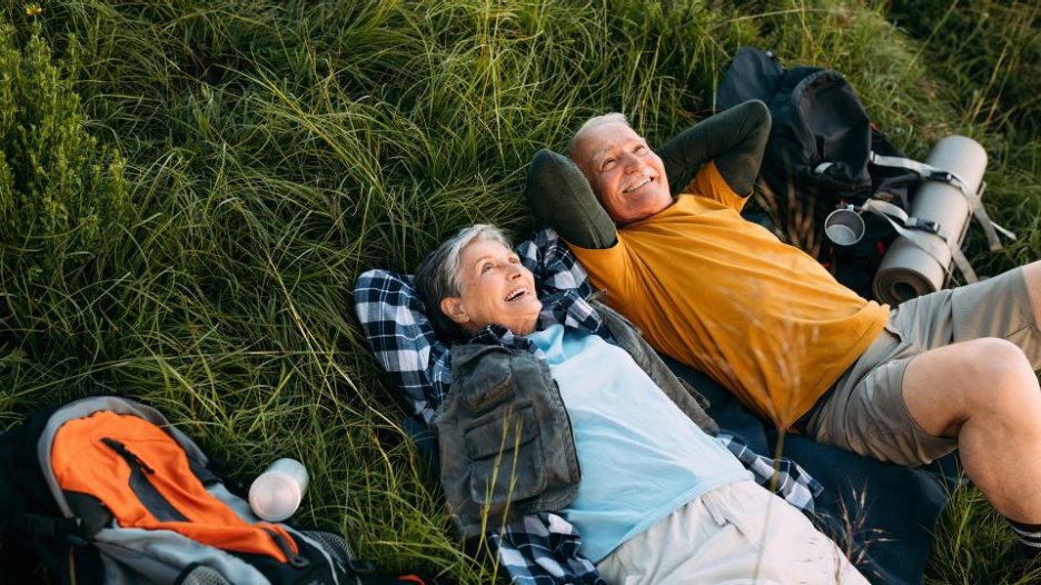 older couple lying in grass and enjoying skies