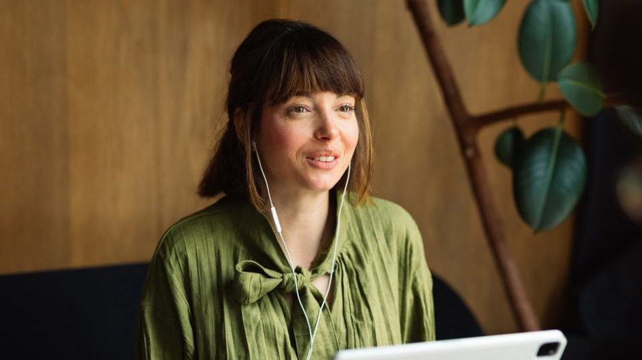 brunette woman with earbuds sitting in café and smiling