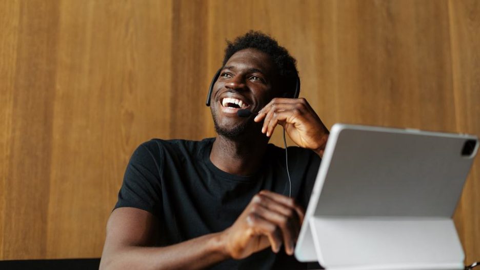 man working in customer service laughing while talking to client