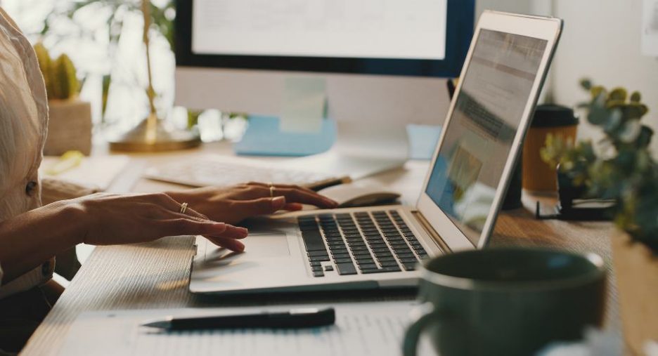 close up of a woman using a laptopat her desk in an office