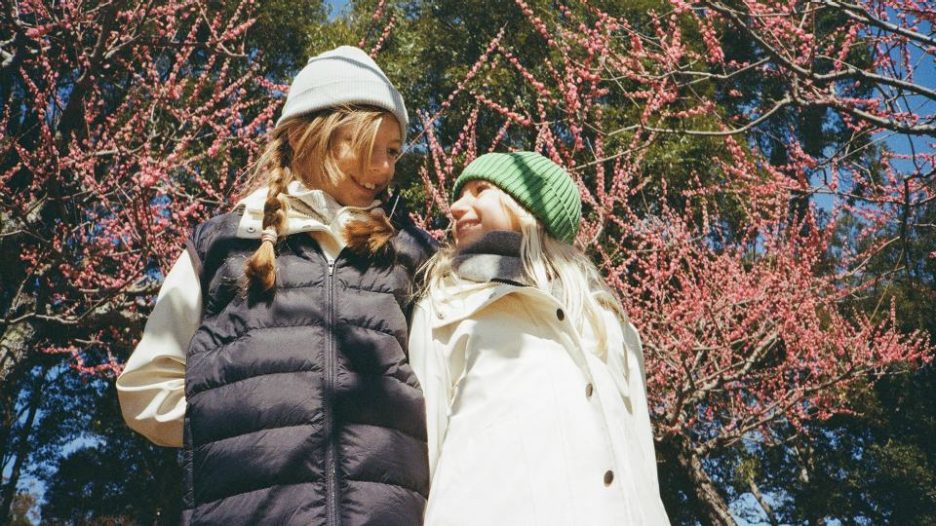 two smiling girls looking at each other outdoors