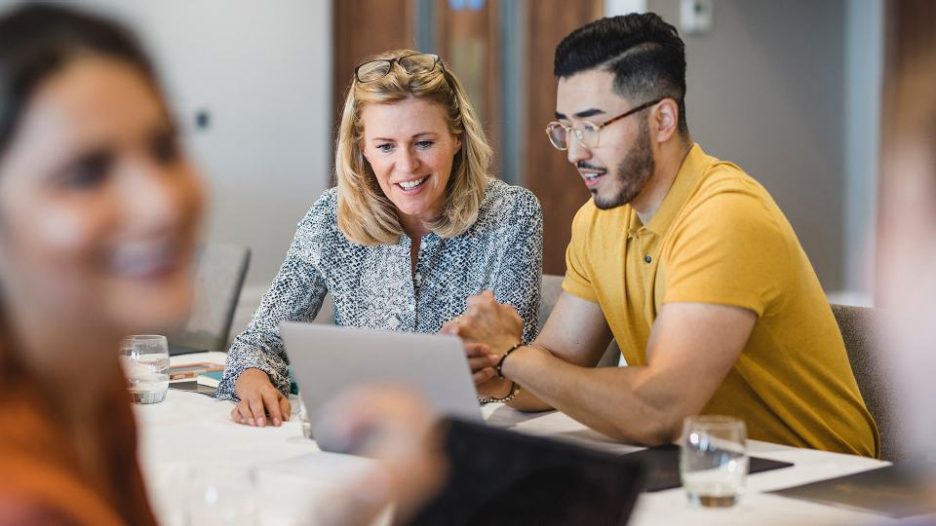 Male and female in discussion while looking at laptop