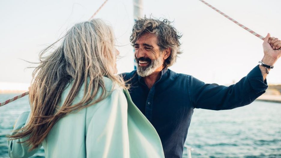 mature carefree man in a navy shirt talking with his wife on a yacht