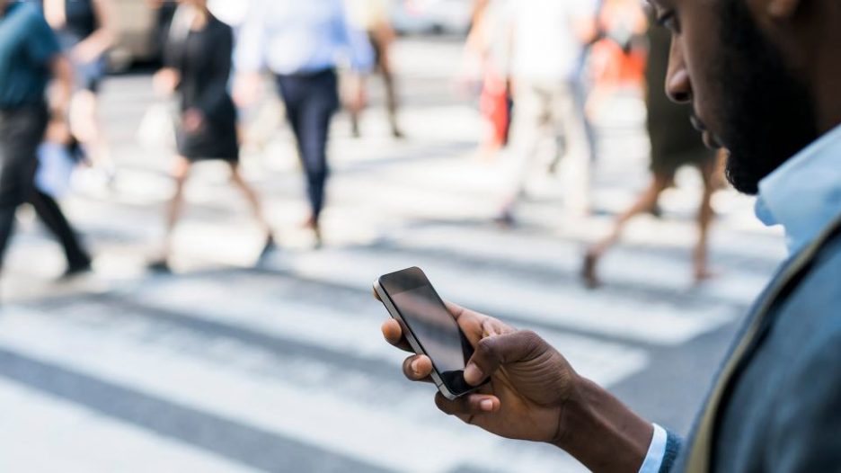 businessman holding a mobile phone in hand and texting in the city