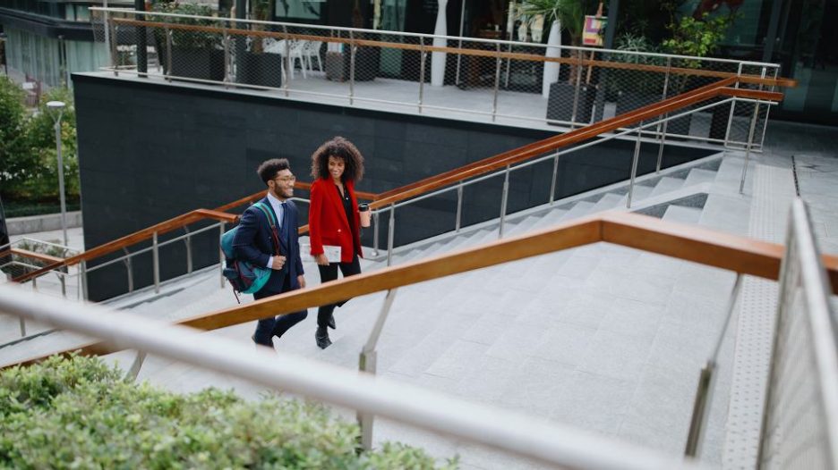 Business people climbing stairs in a modern office full of plants and light