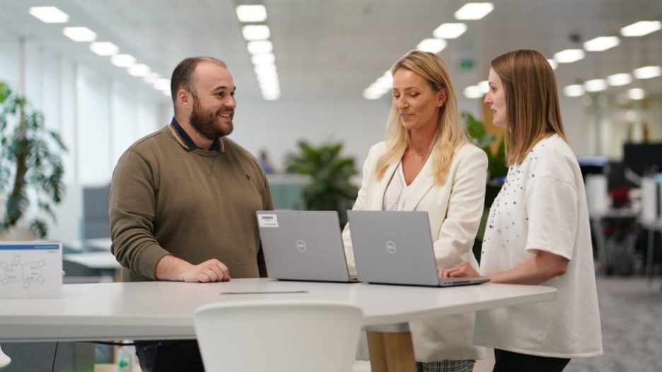Aegon Employees (2 female & 1 male) standing at table around laptops