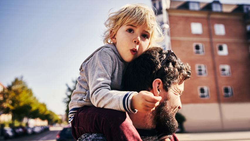 Young child on parents shoulders in resedental area