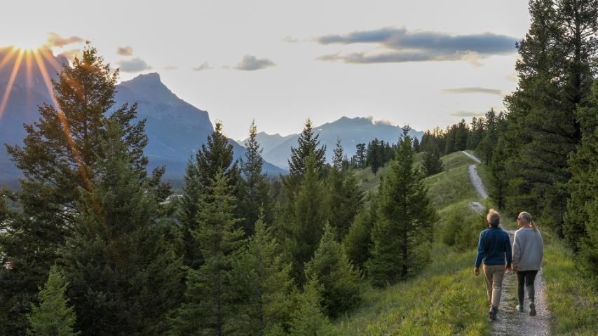 mature couple on a nature walk as the sun sets over the mountains