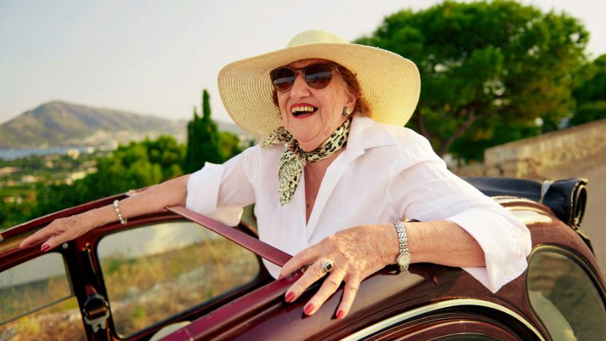 elderly woman with summer hat smiling in back of cabriolet