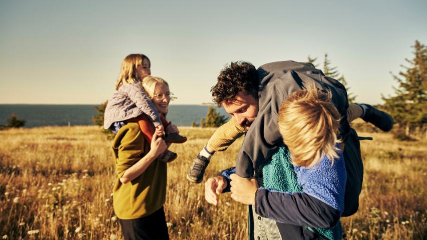 family of four enjoying an afternoon walk in the country with the parents carrying the children