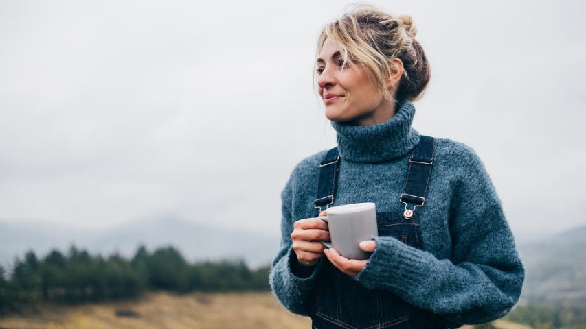 Female holding coffee cup outdoors in the countryside
