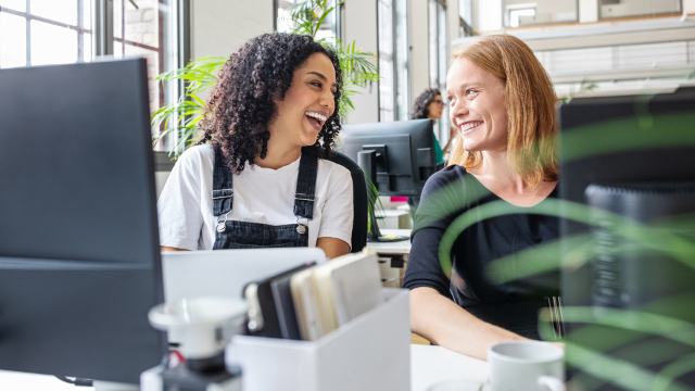 two female colleagues in office laughing