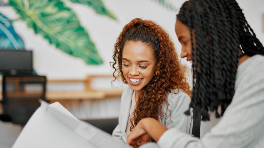 Female couple smiling while looking at paperwork