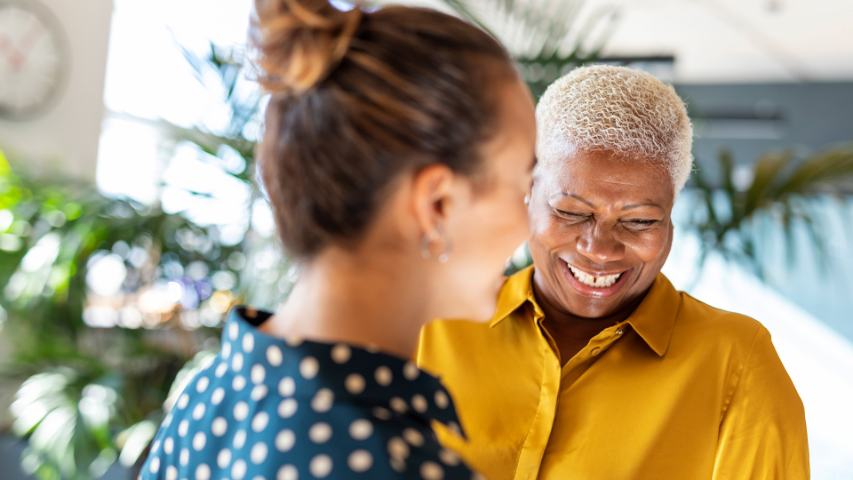 Two professional females laughing in bright office area