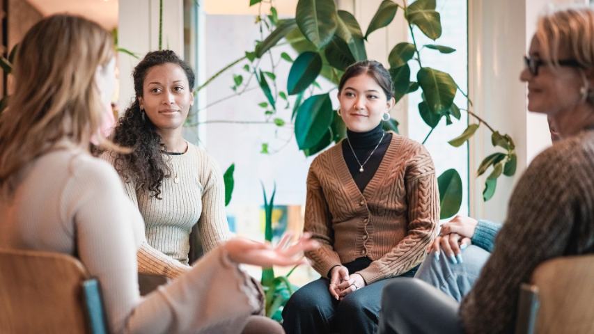 four woman sitting in a group discussion in a modern office setting