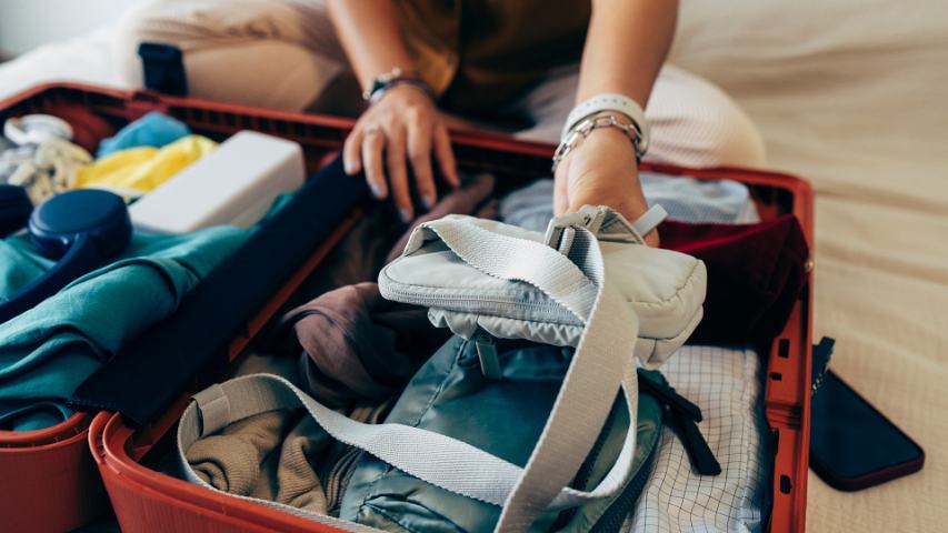 close up of a young person packing a red suitcase