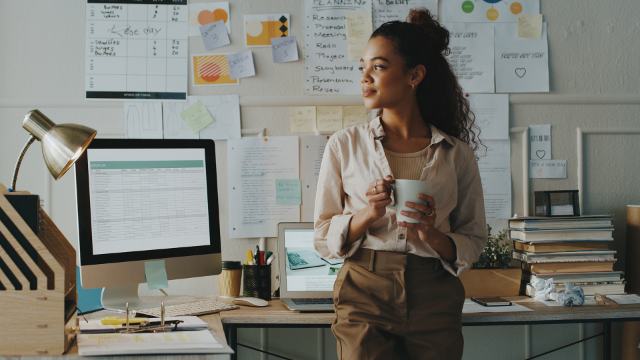 Female in office holding coffee mug and thinking