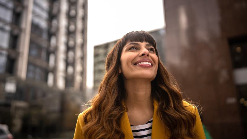 Young professional female looking up and smiling outside in city area