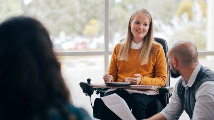 Smiling profesional woman in wheelchair presenting at meeting