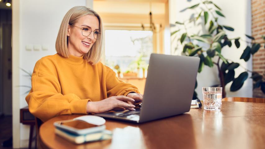 Smiling female sitting at table working on laptop