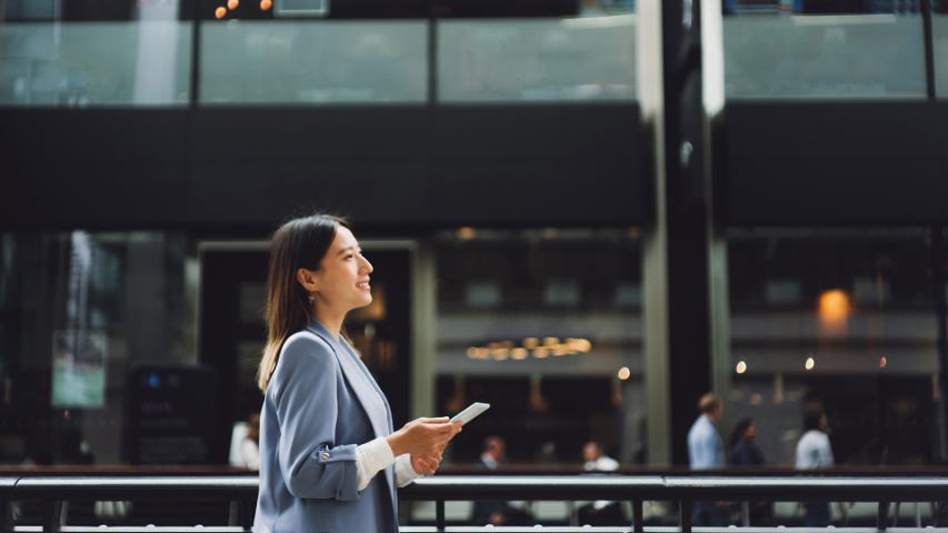 professional woman is walking in the corridor of a modern building with her phone in her hands