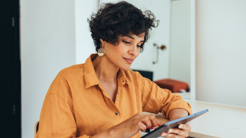 woman in an orange linen shirt is using her ipad in a modern light room