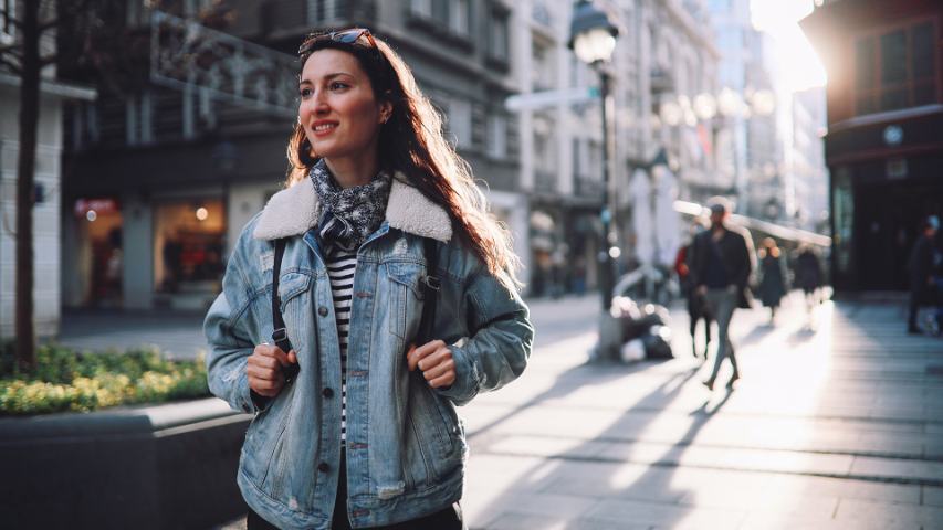 hopeful young woman with backpack and casual clothing on a city street