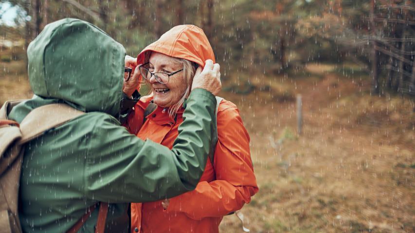 a happy couple adjusting their raincoats on a walk in the rain