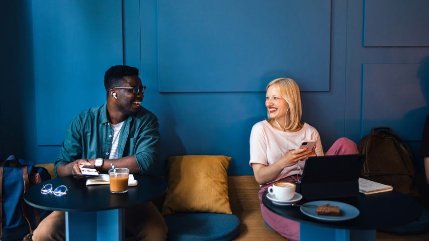 a man and woman working separately at a cafe with blue walls are sharing a moment of connection