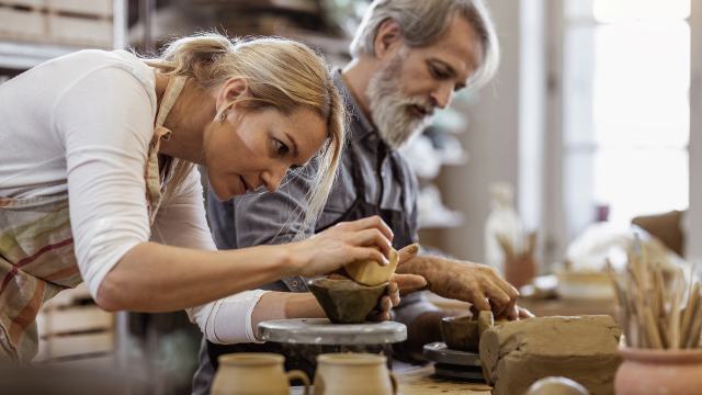 a female and male postter are working with clay in a workshop