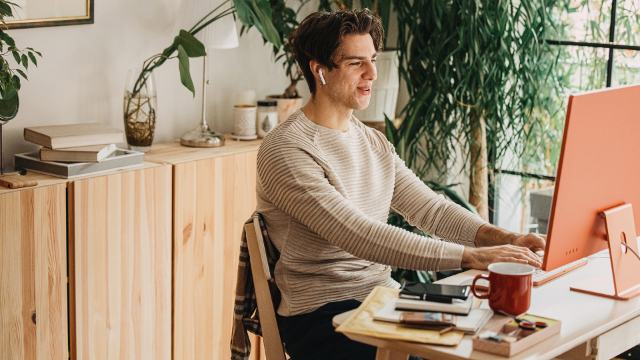 happy man chatting on conference call while in his home office surrounded by plants