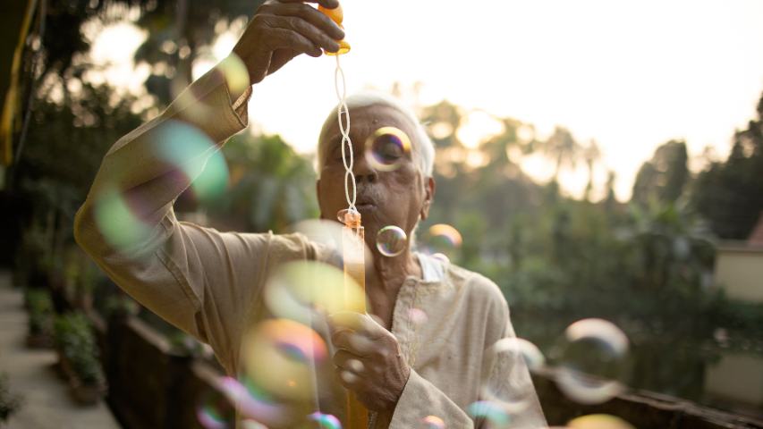 Senior citizen making fun with soap bubbles outdoors