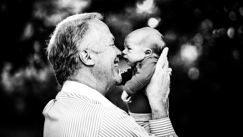 black and white grandfather holding up baby