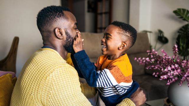 father and young son laughing in livingroom