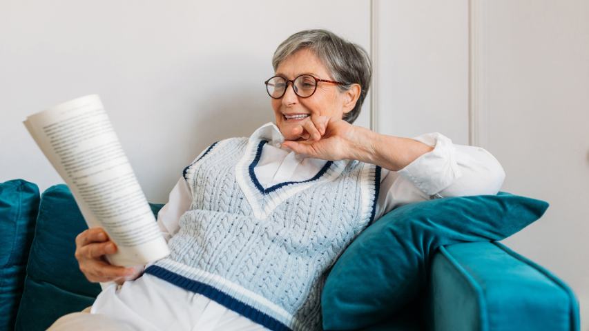 senior woman on couch reading 