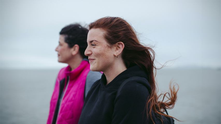 two women smiling on a windy the beach