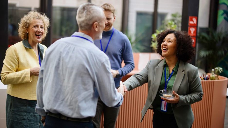 Group of males and females making introductions and shaking hands during a work coffee break