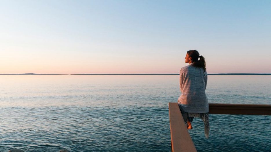 woman sitting on a railing over the water in the late afternoon