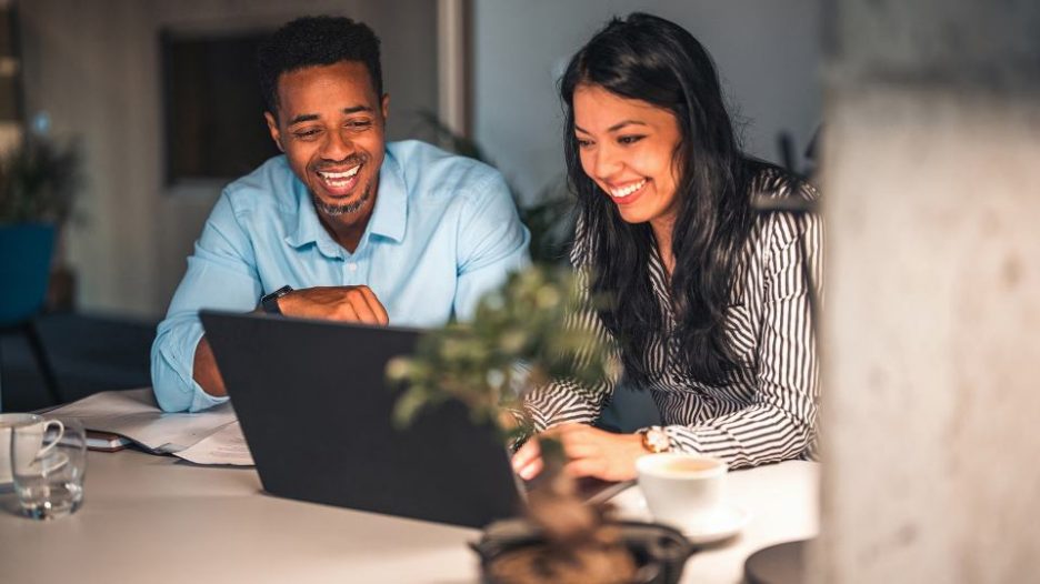 happy smiling man and woman at home looking at a laptop