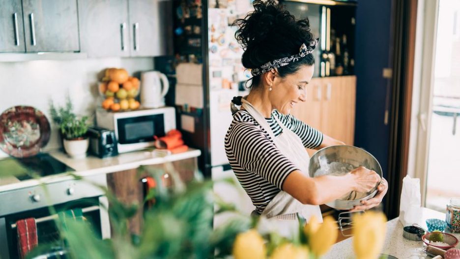 woman in a striped tee shirt enjoying cooking in her kitchen