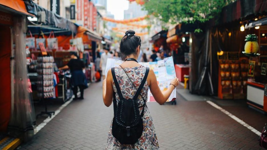woman walking while using a map in a street street