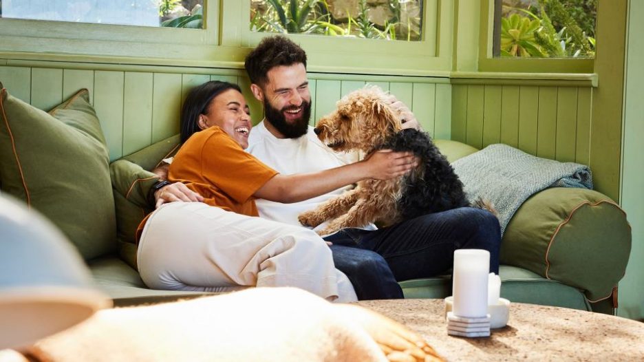 couple at home on their sofa with their dog