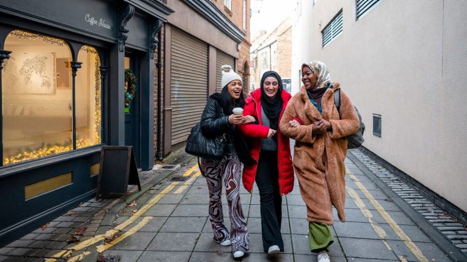 three female friends walking happily together down a city street in cold weather