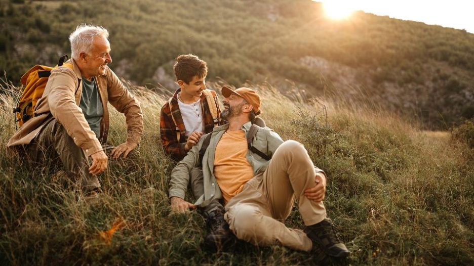 grandfather, father and son are enjoying a relaxing walk in nature at the end of the day