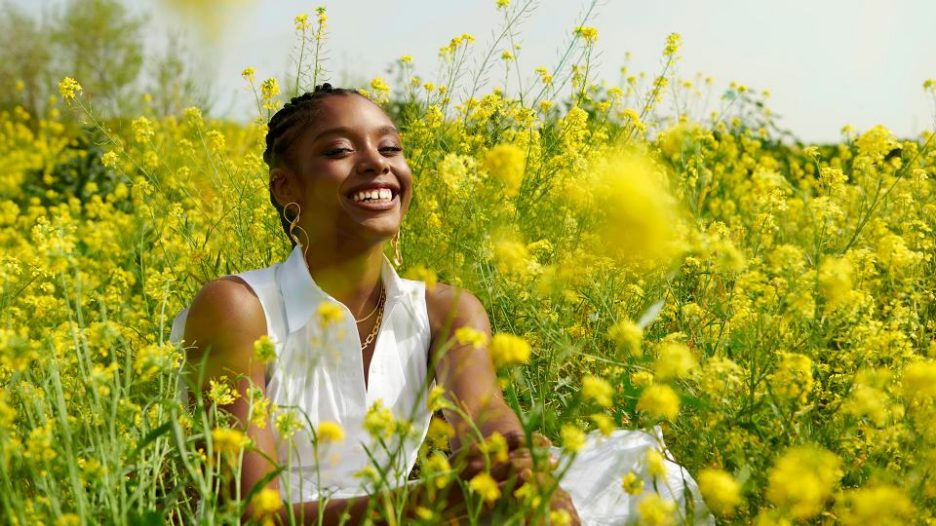 woman sitting in meadow with yellow flowers all around her