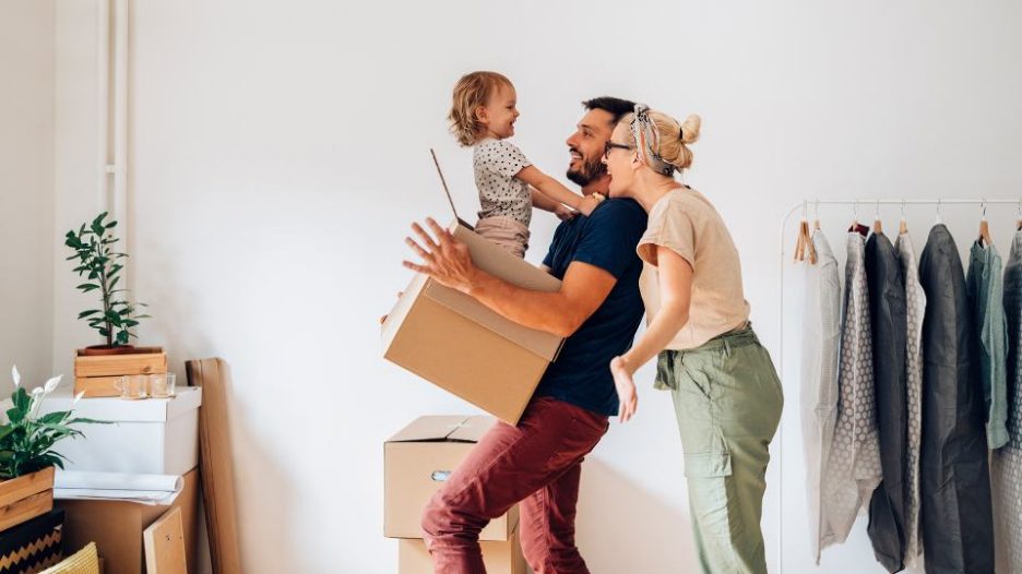 two parents playing with their toddler and a box inside